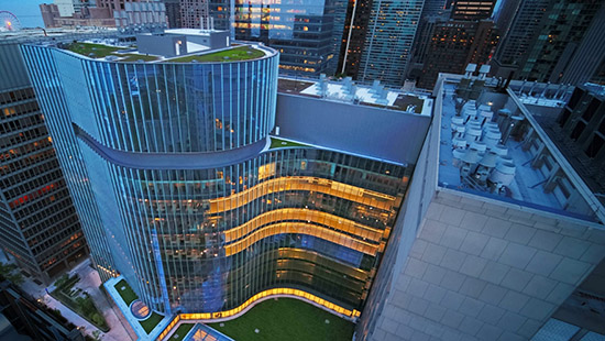 An aerial view of a Feinberg building with windows glowing, at dawn